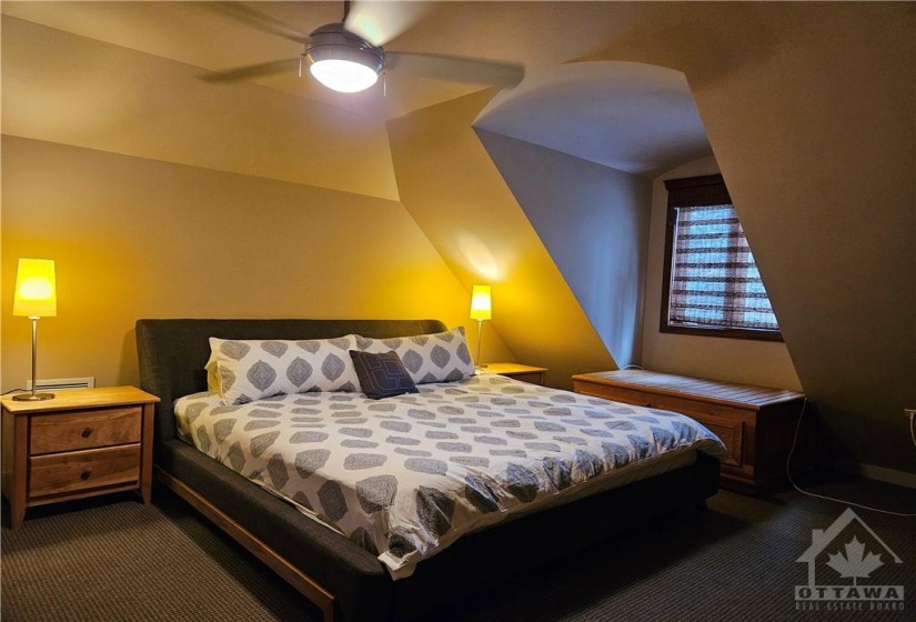 The guest house has this bedroom upstairs with a two piece powder room, carpeted floor and an exposed stone wall for the fireplace in the main room downstairs.