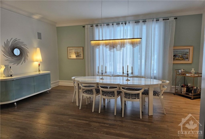 The formal dining room with crown moldings overlooks the backyard, light grey toned hardwood carries throughout the main level. The size of this room will easily accommodate seating for 16. Wall speakers are installed to be used with a Sonos Sound System or an alternate system of your own.