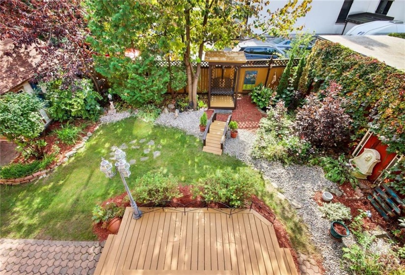 Rear terrace/balcony overlooks the fenced tranquil garden/yard with sitting patio area.