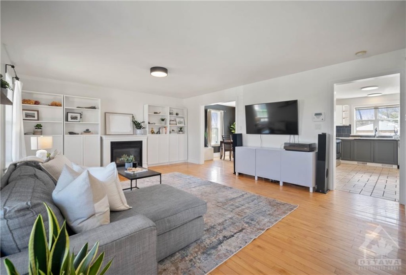 Spacious & bright living room featuring hardwood floors and a cozy gas fireplace.
