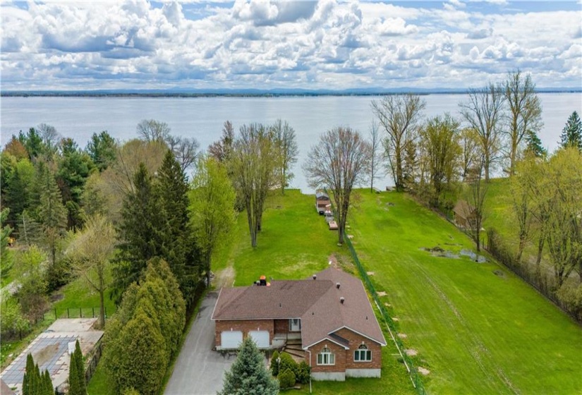 Aerial view of the home overlooking the property and riverfront and the St Lawrence River Shipping Channel plus the Mountains located in New York State in the background