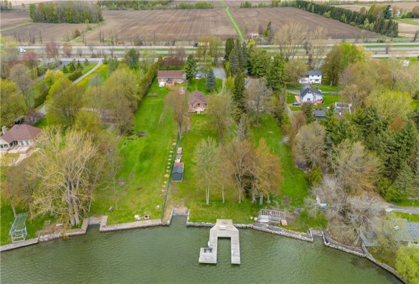 Higher elevated aerial view of permanent boat dock. The owner has brought both water and electricity to the dock area for convenience. The shoreline  stone retaining wall has been built with an area for a boat ramp when needed.