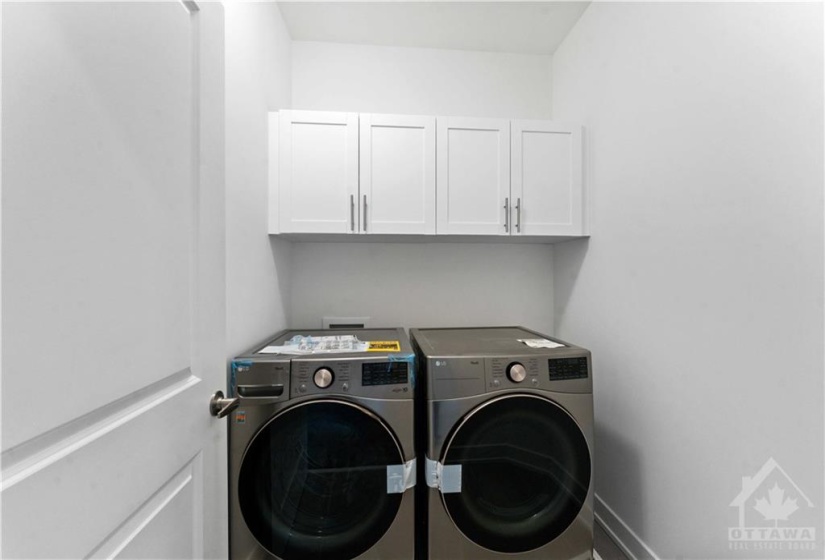 2nd floor laundry room with cabinets above washer dryer