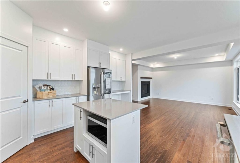 Bright white kitchen with centre island, quartz counters and a walk in pantry