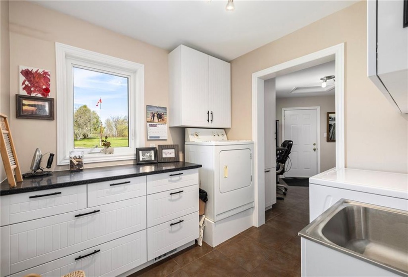Main floor laundry facilities with quartz, new cabinetry.  Shows access to office area and door to attached garage.