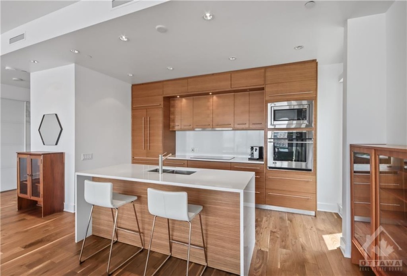 Kitchen with quartz counters and covered fridge blending in with the cabinetry.