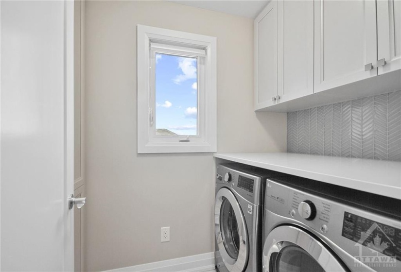 Second floor laundry with custom cabinets and backsplash