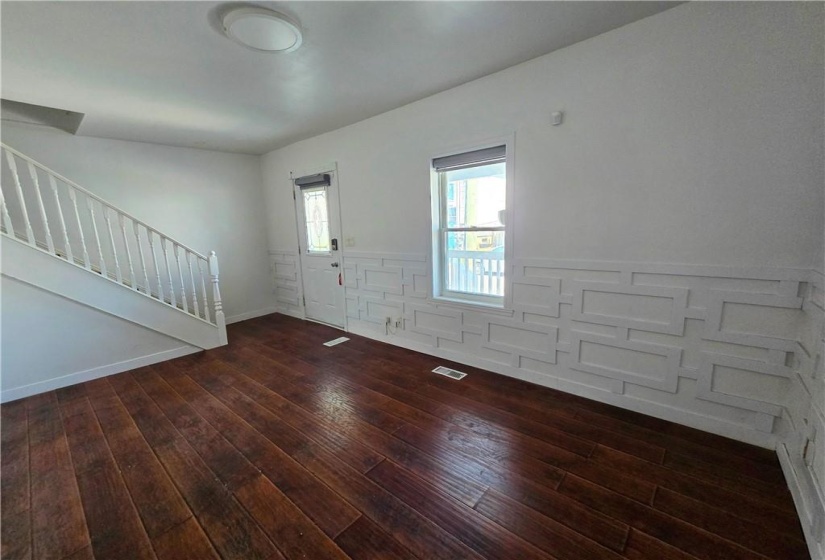 This is the living room of the vacant unit. Notice the newly added woodwork on the walls creating a modern, architectural vibe. There is new flooring installed throughtout.