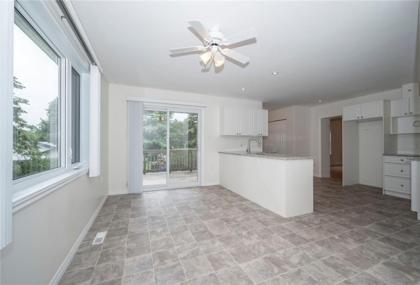 Sunny bright kitchen with dining area leading to deck overlooking back yard