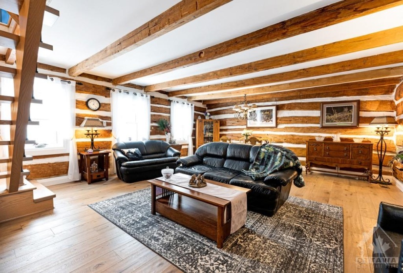 Spacious living room lots of windows, hardwood floor and exposed logs