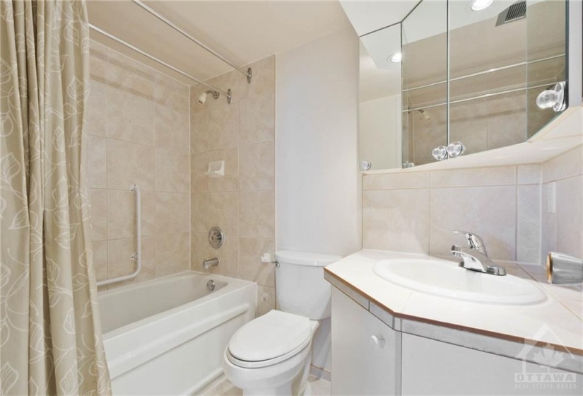 Main Bathroom with full tub tiling and decor mirrors.