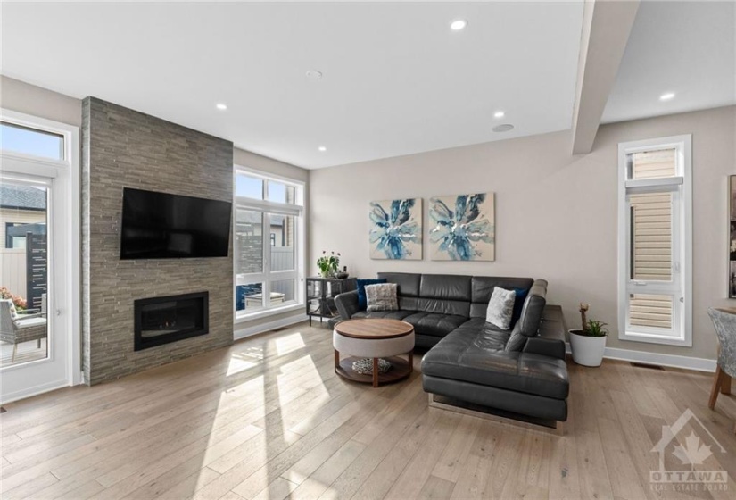 Living room w/ gas fireplace and tons of windows welcoming natural light.