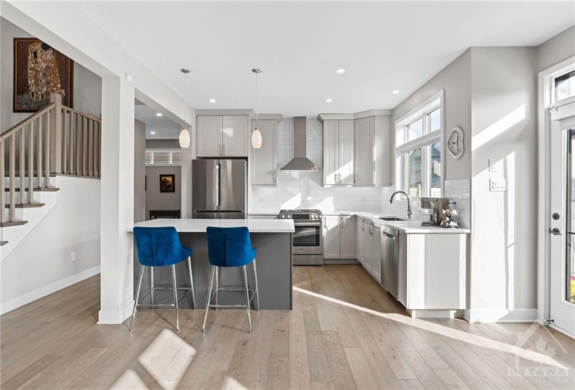 Kitchen includes quartz island w/ breakfast bar seating and elegant tile backsplash.