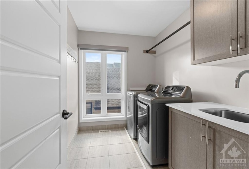 Laundry suite w/ sink and plenty of storage space above.