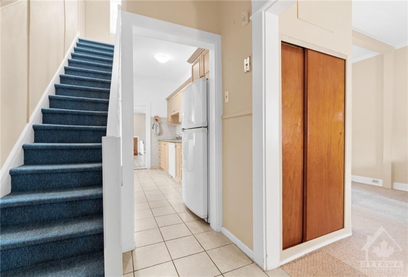 Front entryway- Double door front closet, carpeted stairs to 2nd level and tiled kitchen.