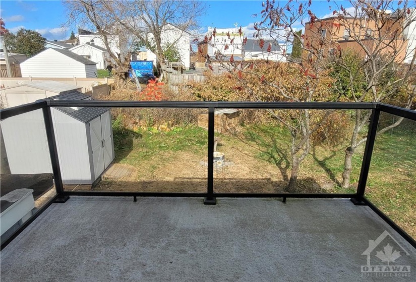 View of the yard from the balcony. Note the new glass panels. One can see the shed, hen house in the rear and fire pit.