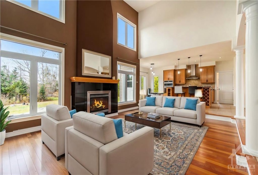 Soaring 21-foot ceilings, a cozy gas fireplace, and oversized windows create a bright and inviting living room.  (Virtually staged)