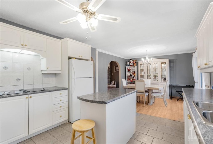 View of the adjoining eating area, the Jenn-air cook-top and the tile flooring in this picture.